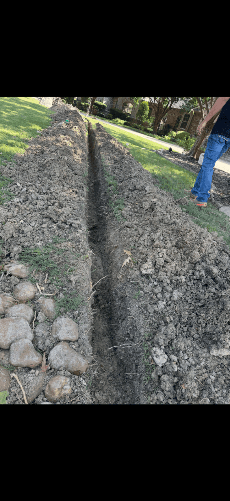 French drain trench dug through a front yard to correct drainage problems
